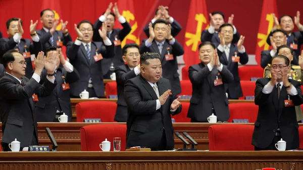 Delegates attend the Workers' Party Congress in Pyongyang with red folders and party emblems on stage.