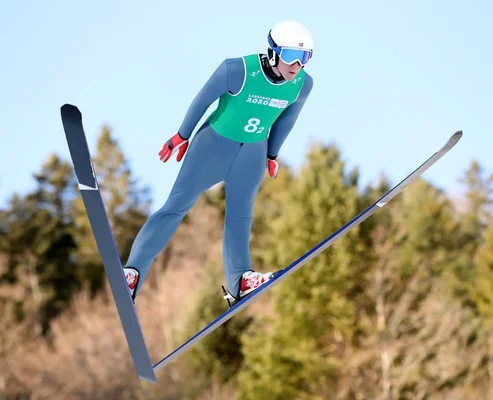 Skieur dévalant une piste de ski ensoleillée dans les Alpes françaises, montagnes enneigées en arrière-plan