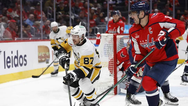 Sidney Crosby and Alexander Ovechkin facing off on the ice.