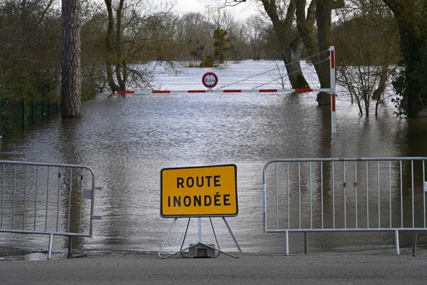 Une route inondée barrée par un panneau d'avertissement lors des crues dans le Maine-et-Loire.