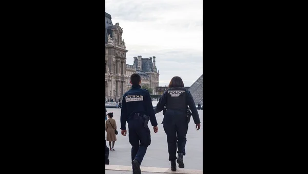 Des policiers en uniforme circulant sur la place du Louvre.