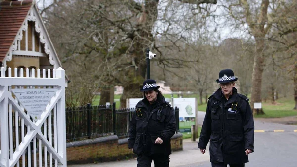 Des policiers britanniques en uniforme patrouillant près d'une entrée barrée.