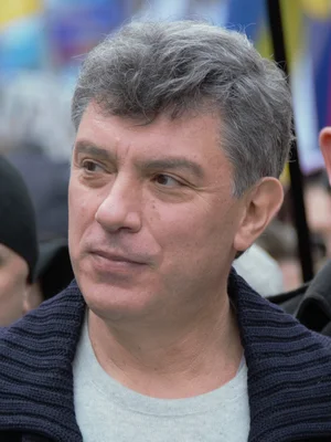 Boris Nemtsov en 2014, portant un col tricoté bleu foncé sur une chemise grise claire, lors d'un événement extérieur.