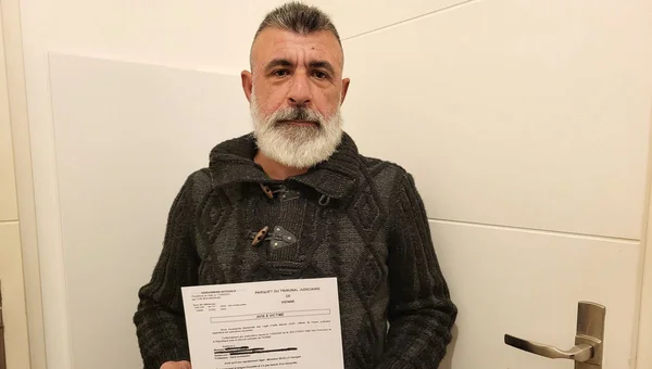 Un père tenant un document du Parquet après avoir retrouvé l'agresseur de sa fille