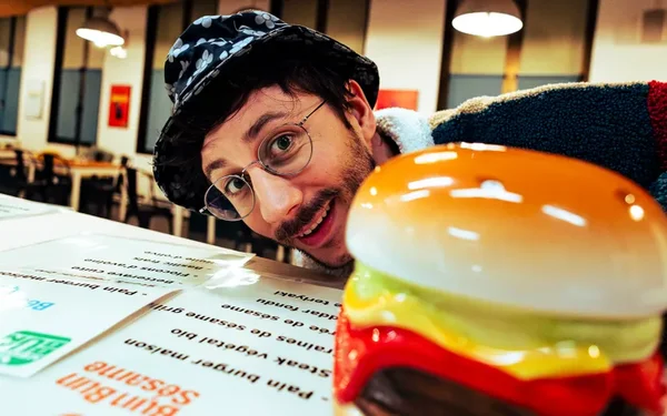 Un participant devant le burger géant de la comédie Les Burgers sanglants.