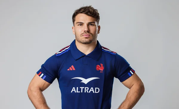 Joueur de rugby debout devant un fond gris portant le maillot bleu de l'équipe de France.