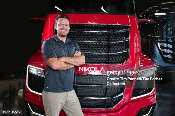 Trevor Milton posant devant un camion rouge de la marque Nikola.