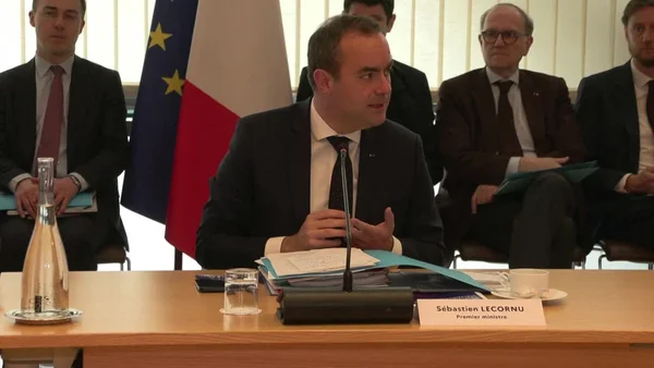 Sébastien Lecornu lors d'une conférence officielle, drapeaux français et européens derrière lui.