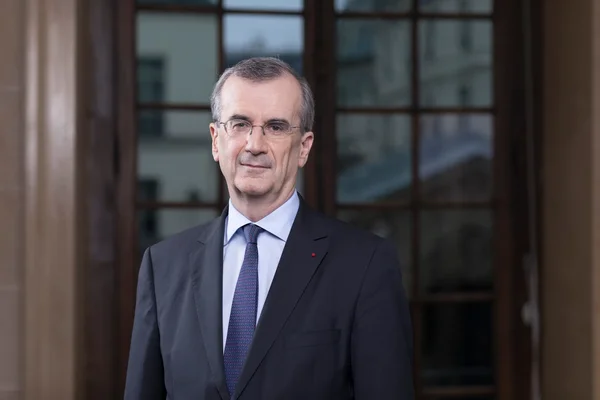 François Villeroy de Galhau pose devant un bâtiment vitré lors d'une apparition publique.