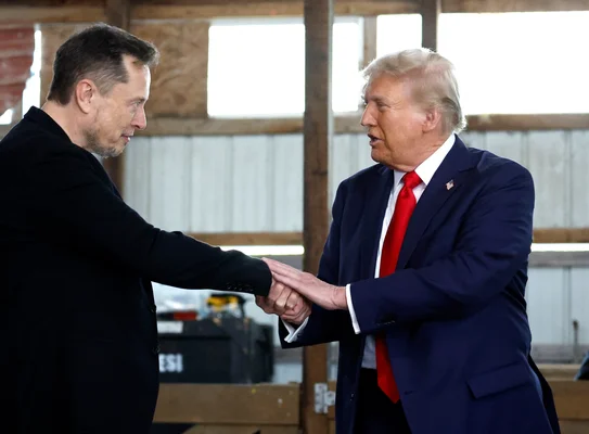 Deux hommes en costume d'affaires serrant la main dans un décor industriel.