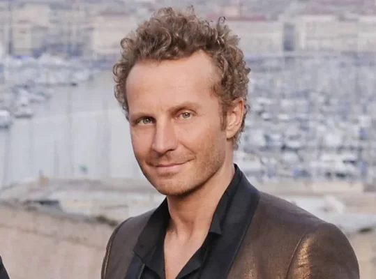 Sinclair debout devant un paysage marin.