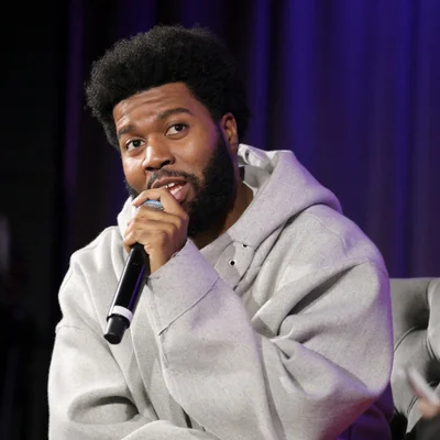 Khalid avec un micro devant un fond sombre lors d'une apparition publique.