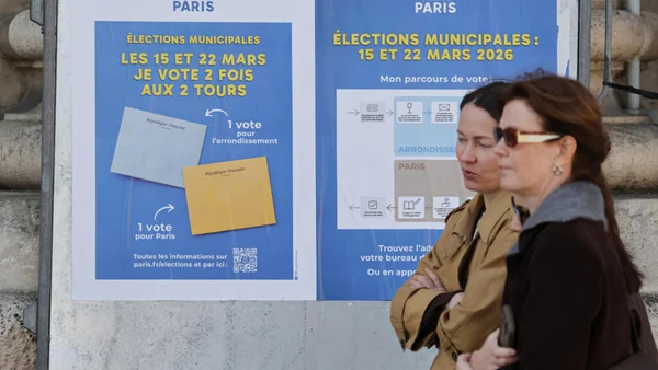 Deux femmes devant une affiche d'information officielle sur les modalités de vote pour les municipales à Paris.