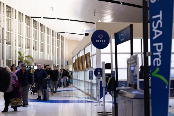 Passagers marchant dans un couloir de sécurité près de panneaux TSA Pre✓.
