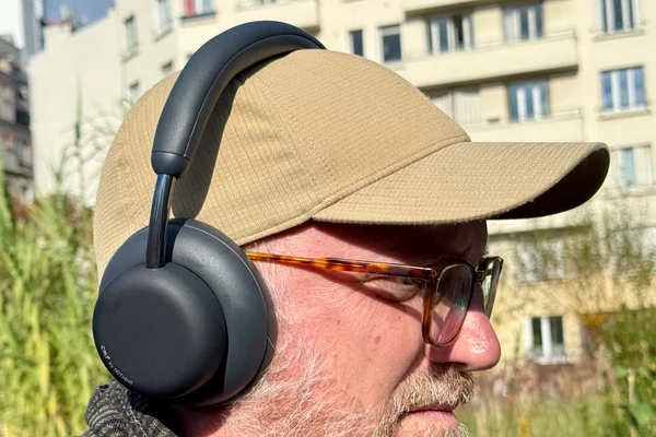 Un homme portant des écouteurs Beats bleus en extérieur.