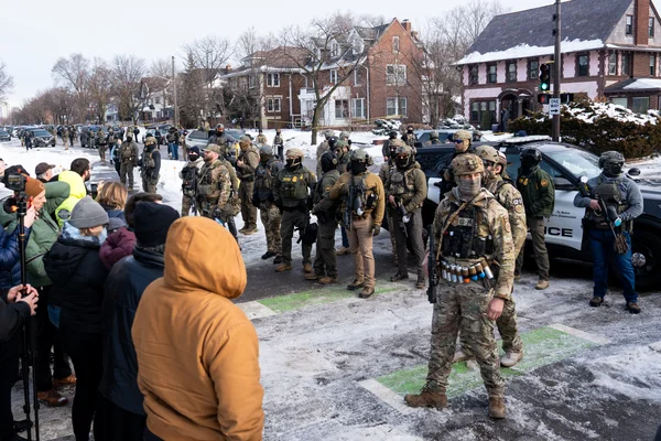 Officiers tactiques armés déployés dans une rue résidentielle de Minneapolis après une intervention de l'ICE.