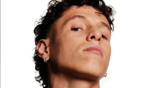 Le chanteur Danyl Semmache, micro à la main, posant avec une chemise bordeaux sur un fond obscur.