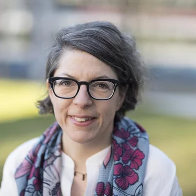 Petra Volpe, scénariste et réalisatrice, souriant devant un fond de verdure.