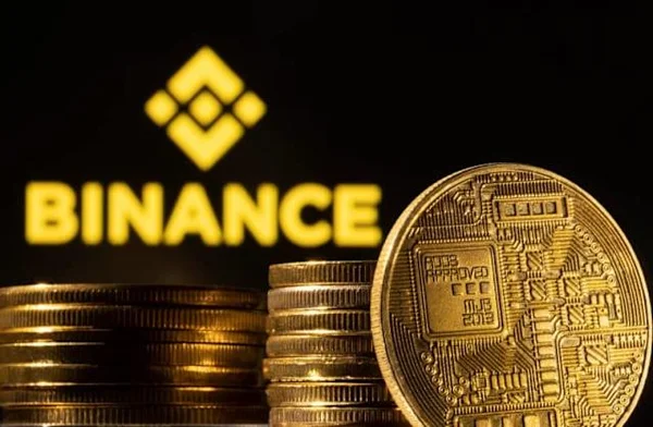 Logo Binance entouré de piles de pièces d'or sur fond noir.