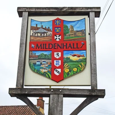 Panneau de la ville de Mildenhall avec blason et symboles, ciel nuageux en arrière-plan