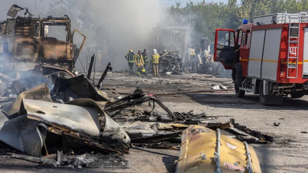 Des camions calcinés et des débris jonchent le sol après un incendie violent.