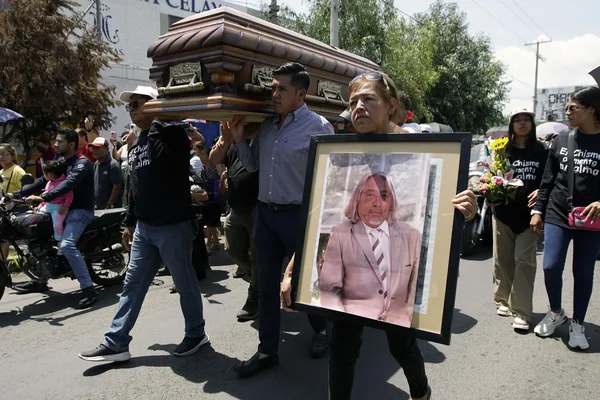 Un cortège funèbre transportant un cercil lors d'une cérémonie dans la rue.