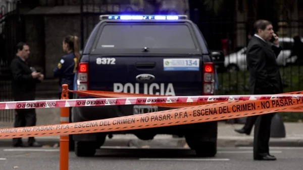 Véhicule de police derrière le ruban de scellé de la PFA indiquant 'scène du crime'.