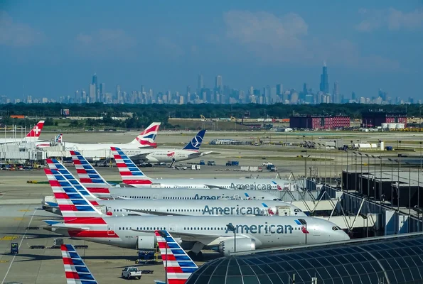 Avions d'American Airlines garés au port d'embarquement avec la skyline d'une ville américaine en arrière-plan.