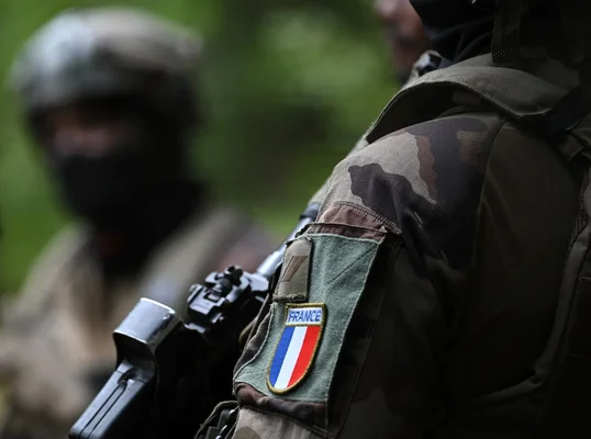 Soldat français en opération avec son arme et son insigne.