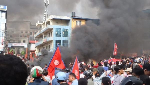Manifestation avec fumée noire et drapeaux rouges lors du soulèvement des jeunes au Népal.