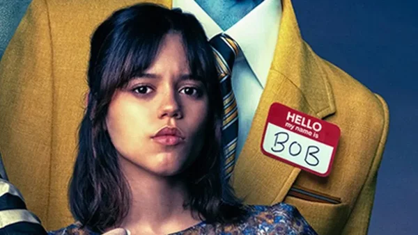 Une femme en premier plan devant un homme portant un costume jaune et un badge Hello my name is BOB.