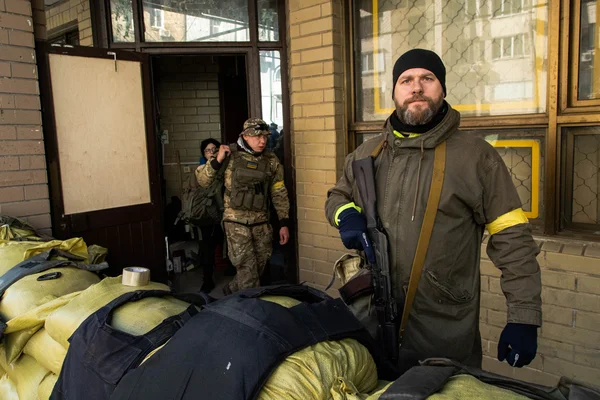 Un civil armé avec un brassard jaune des Forces de défense territoriale devant des sacs de sable à Kyiv.