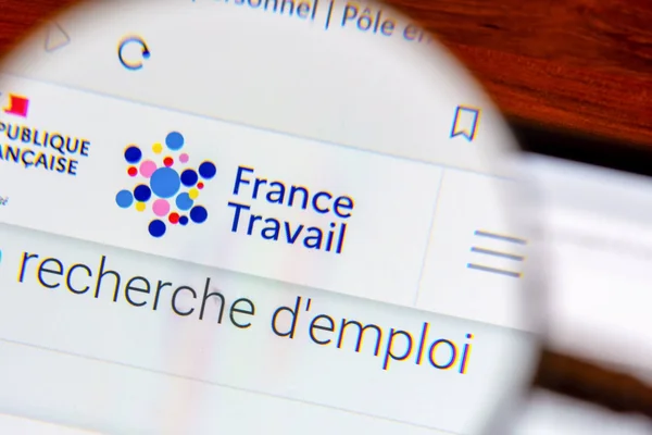 Gros plan à travers une loupe de l'interface du site France Travail affichant la section 'recherche d'emploi'.