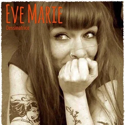 Evemarie, dessinatrice, photographiée de face avec ses longs cheveux bruns et ses tatouages.