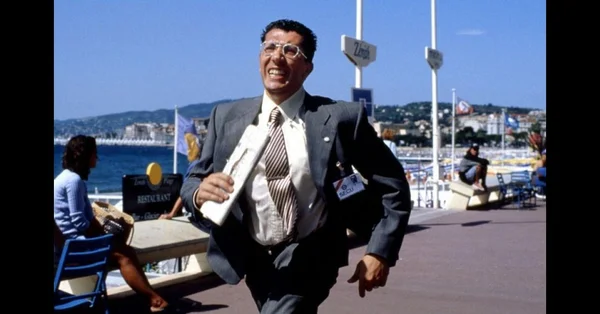 Scène d'action dans La Cité de la peur avec un personnage en costume courant le long d'un front de mer urbain.