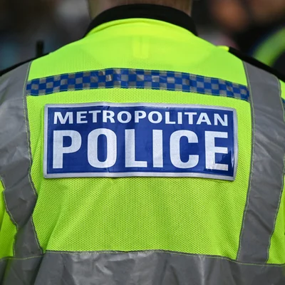 Trois véhicules de police stationnés devant un bâtiment avec une statue en arrière-plan.