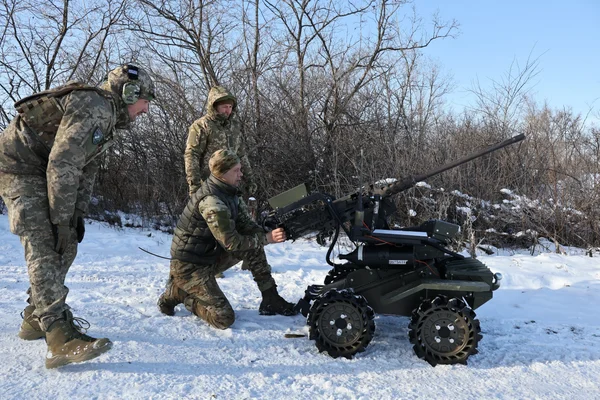 Soldats ukrainiens entraînant un robot militaire chenillé dans un environnement hivernal.