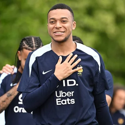 Kylian Mbappé en maillot des Bleus, la main sur le cœur, au milieu de ses coéquipiers.