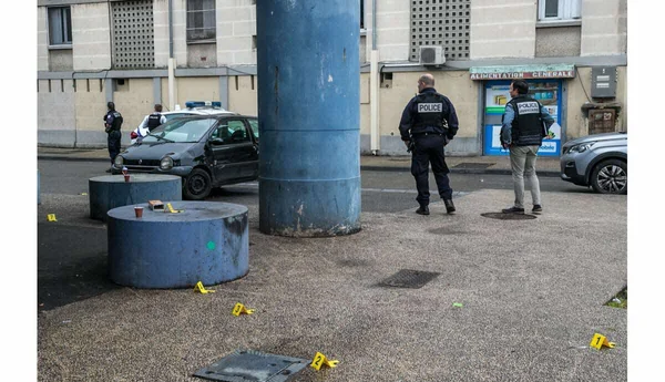 Des policiers enquêtent sur des repères numérotés près d'une épicerie 'Alimentation générale'.