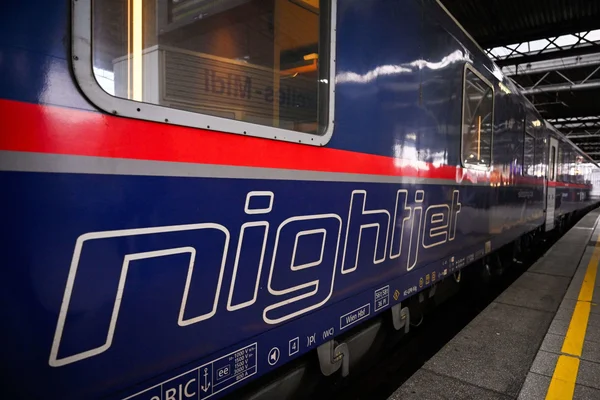 Un train Nightjet bleu stationné sur un quai de gare.
