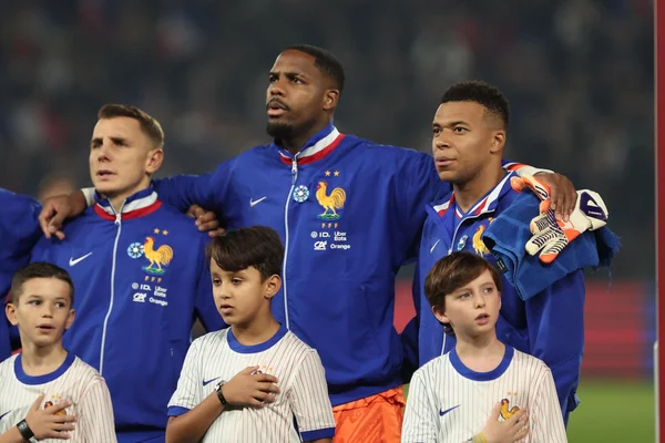Les joueurs de l'équipe de France, dont Mbappé, entourent des enfants lors d'un match.