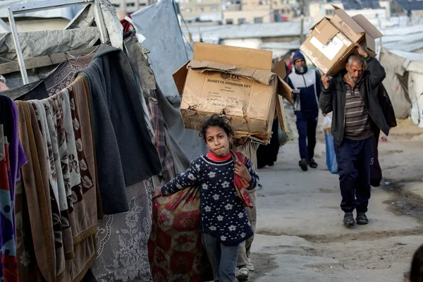 Une jeune fille dans un camp de réfugiés à Gaza, au milieu des tentes et de l'aide humanitaire.