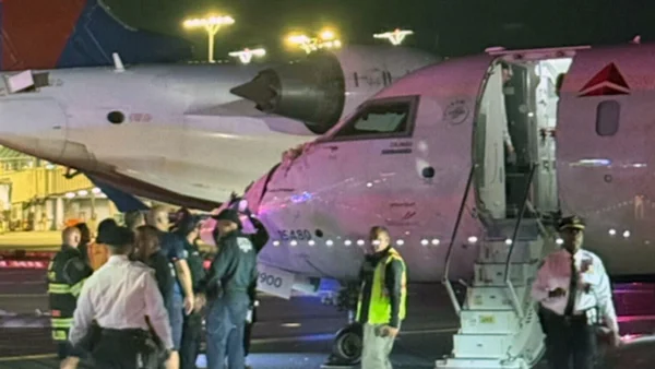 Secouristes près d'un avion rose sur le tarmac la nuit.
