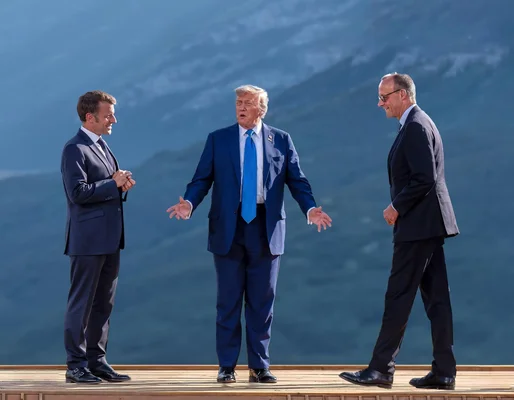 Un groupe de personnes en costume sous un drapeau américain, l'une levant le poing.