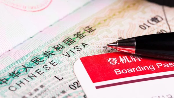 Un visa chinois et une carte d'embarquement disposés côte à côte.