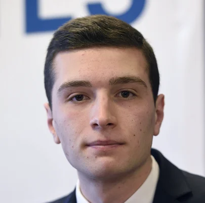 Photographie rapprochée de Jordan Bardella en veste sombre.