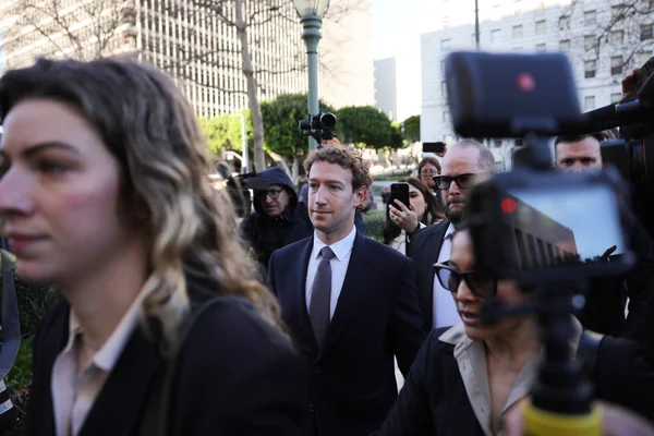 Mark Zuckerberg marchant à l'extérieur, entouré par des photographes et des médias.