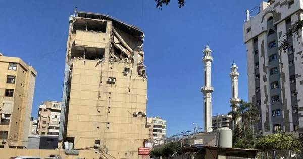 Immeuble détruit devant une mosquette, témoignant des dégâts dans la banlieue sud.