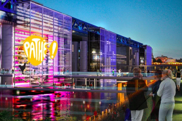Le bâtiment du cinéma Pathé La Villette éclairé la nuit avec son logo visible.