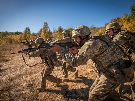 Soldats ukrainiens en position de tir dans une zone sèche et boisée au front.